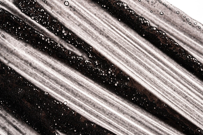 Close-up of Obsidian charcoal scalp scrub's black and white swirled texture